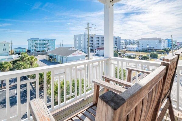 A balcony with a view of a coastal town, featuring buildings and a clear sky.