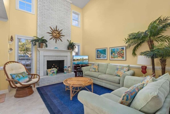 A living room with a fireplace, a sofa, a chair, and a television.