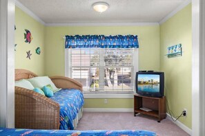 A room with a bed, a television, and a window with blinds.