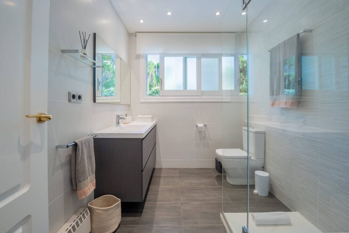 Un baño moderno con cabina de ducha de vidrio, tocador con lavabo e inodoro.