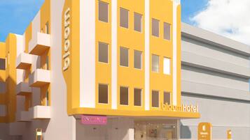 Un hotel moderno con fachada amarilla, balcones y un letrero que dice 'bloom Hotel'.