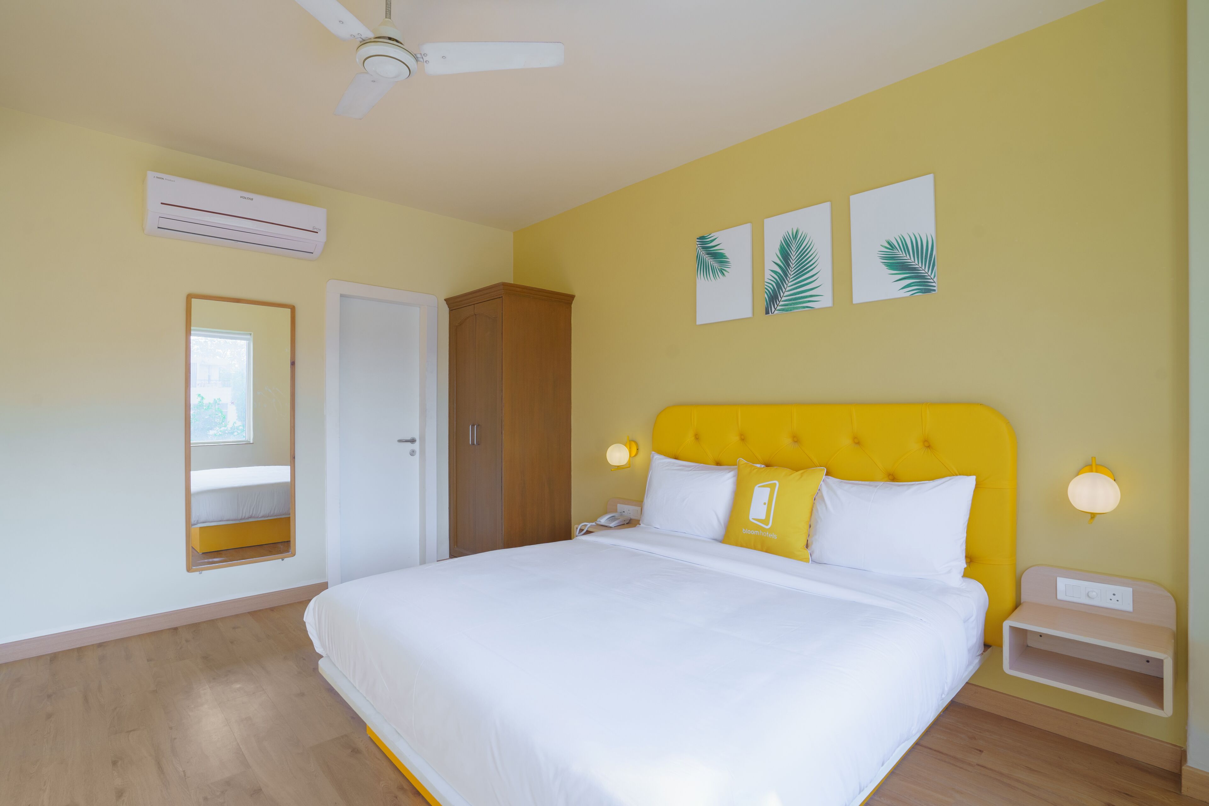 A bedroom with a bed, a wardrobe, a mirror, and a ceiling fan.