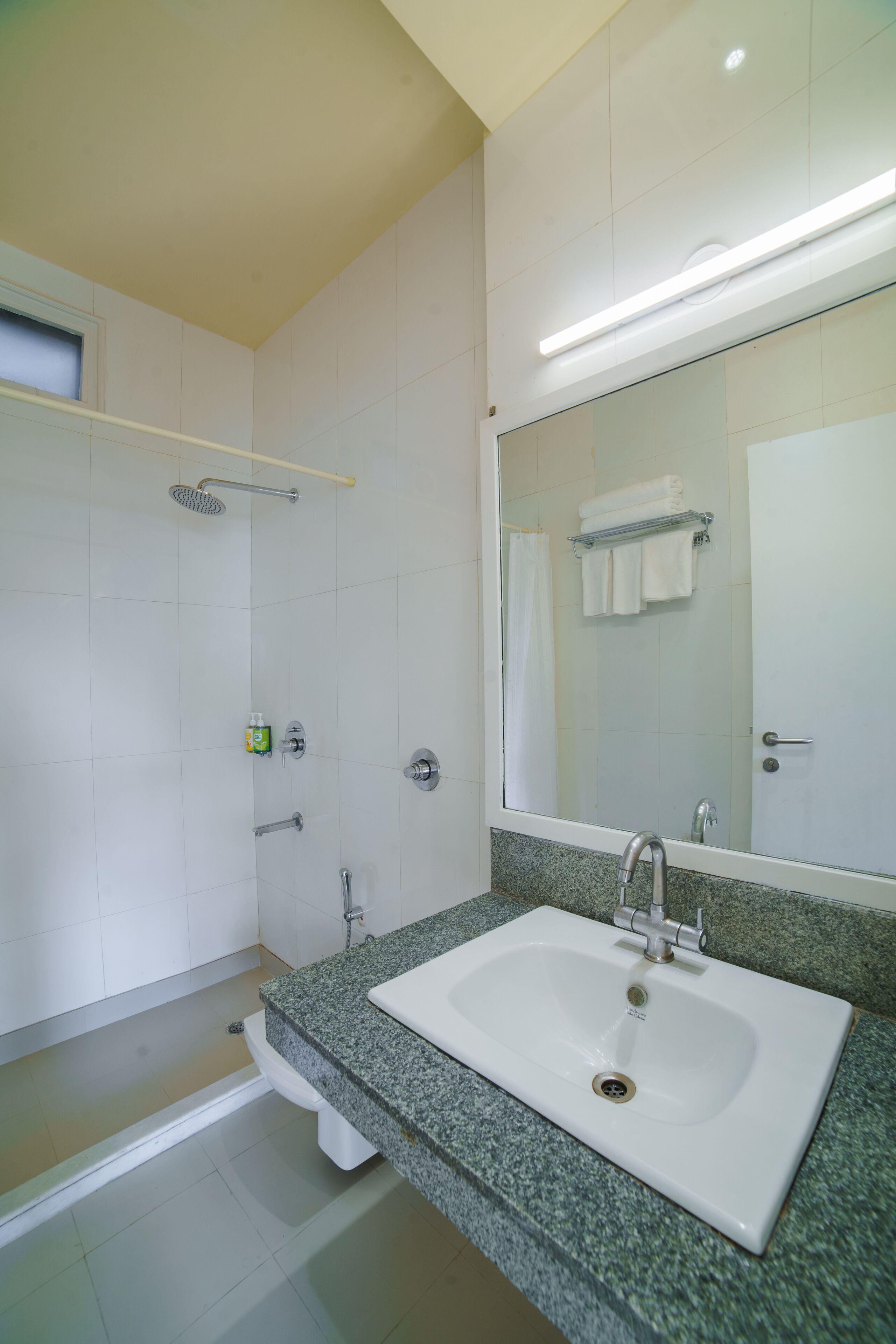 Ein modernes Badezimmer mit einem weißen Waschbecken, einer Granit-Arbeitsplatte und einem großen Spiegel.