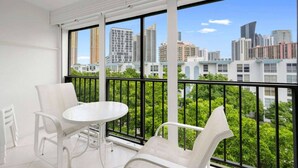 A balcony with a white table and chairs, large windows offering a city view, and a metal railing. - le cartier sunny isles ocean paradise (Sunny Isles Beach)