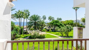 A balcony with a view of a well-maintained garden and a clear blue sky. - Parque Mar Apartments (Santanyi)