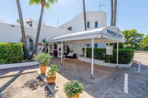 A hotel entrance with a covered patio, palm trees, and potted plants. - Parque Mar Apartments (Santanyi)