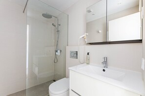 A modern bathroom with a glass shower enclosure, a white sink, and a mirror above the sink. - Parque Mar Apartments (Santanyi)