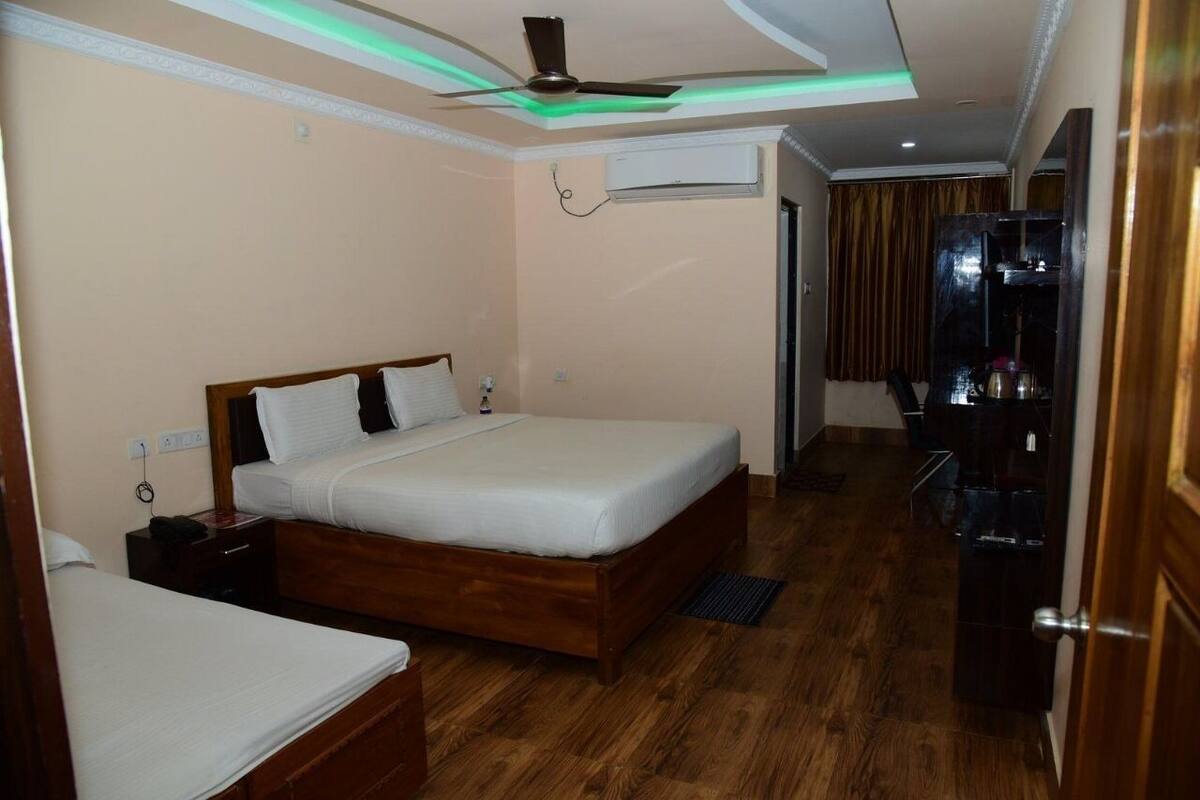 A hotel room with a wooden bed, a nightstand, an air conditioning unit, and a ceiling fan.