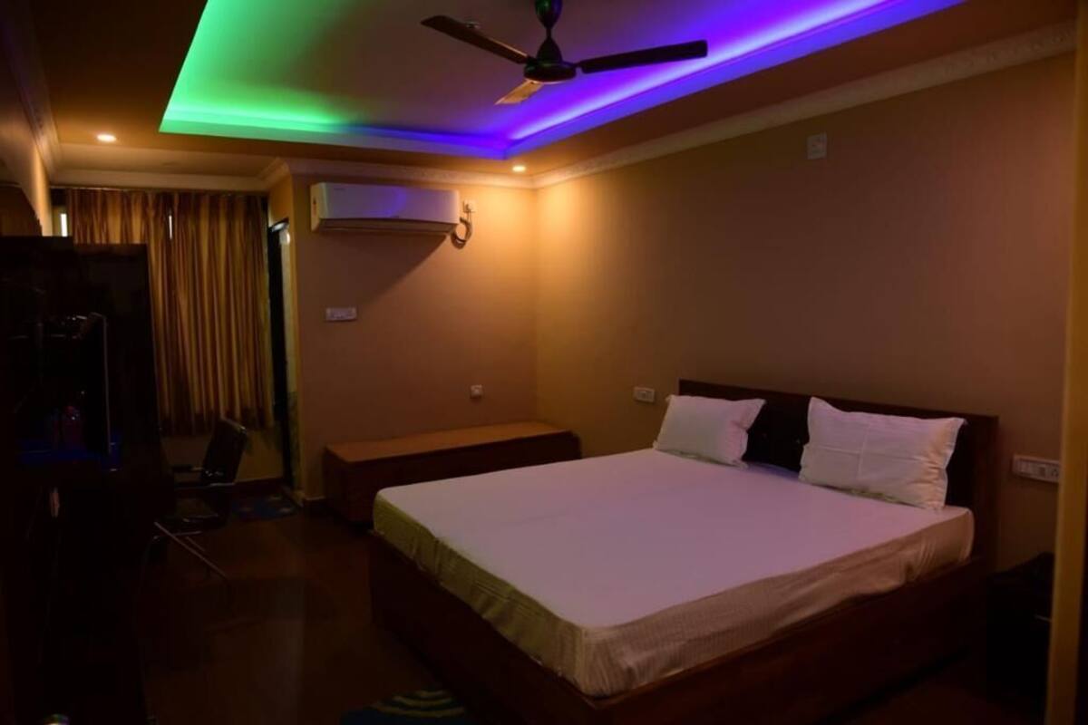 A hotel room with a bed, a ceiling fan, and an air conditioning unit.
