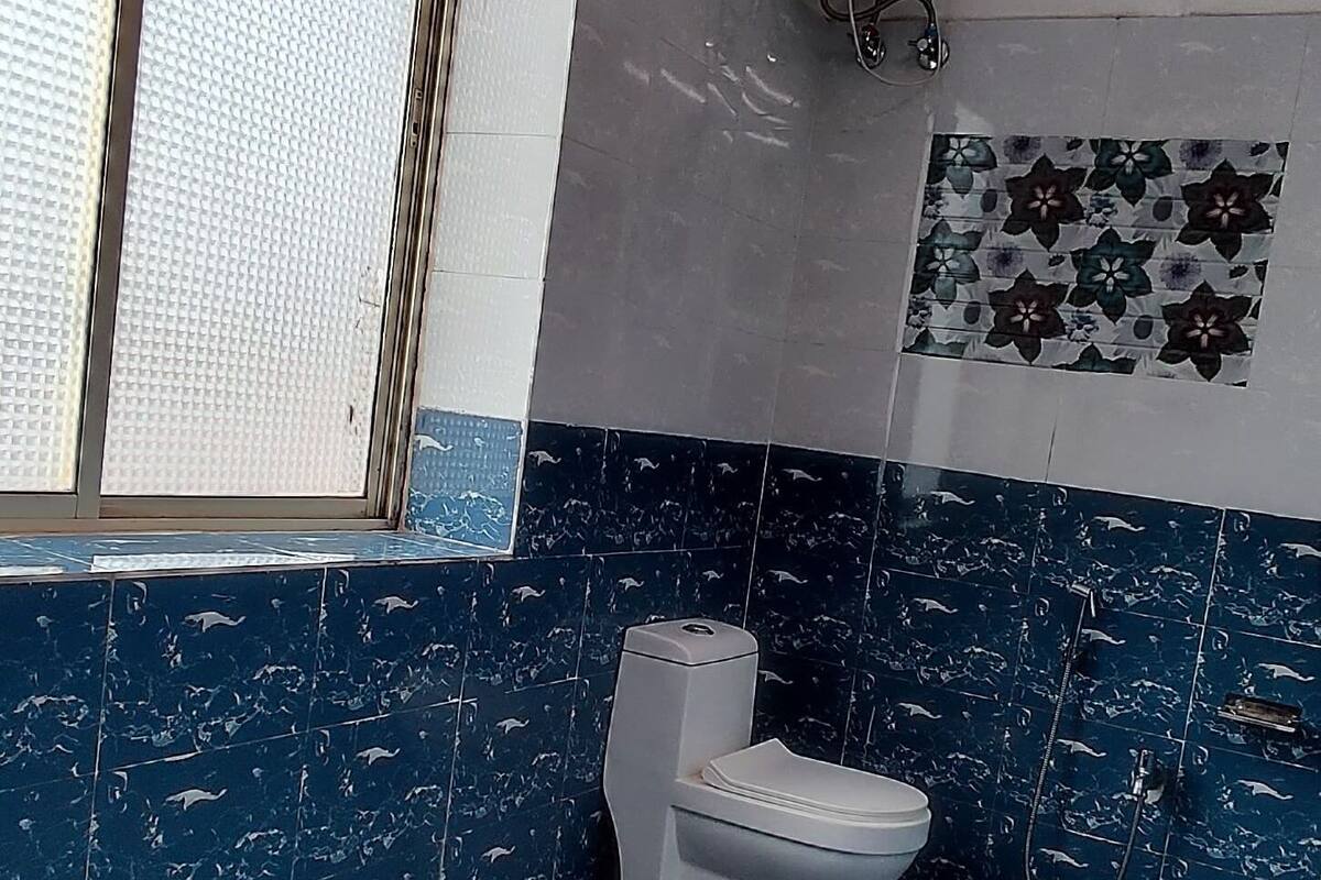 A bathroom with a toilet, a shower, and a window.