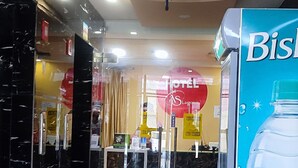 Un vestíbulo de hotel con una recepción, un anuncio grande de agua Bisleri y un cartel visible del hotel.