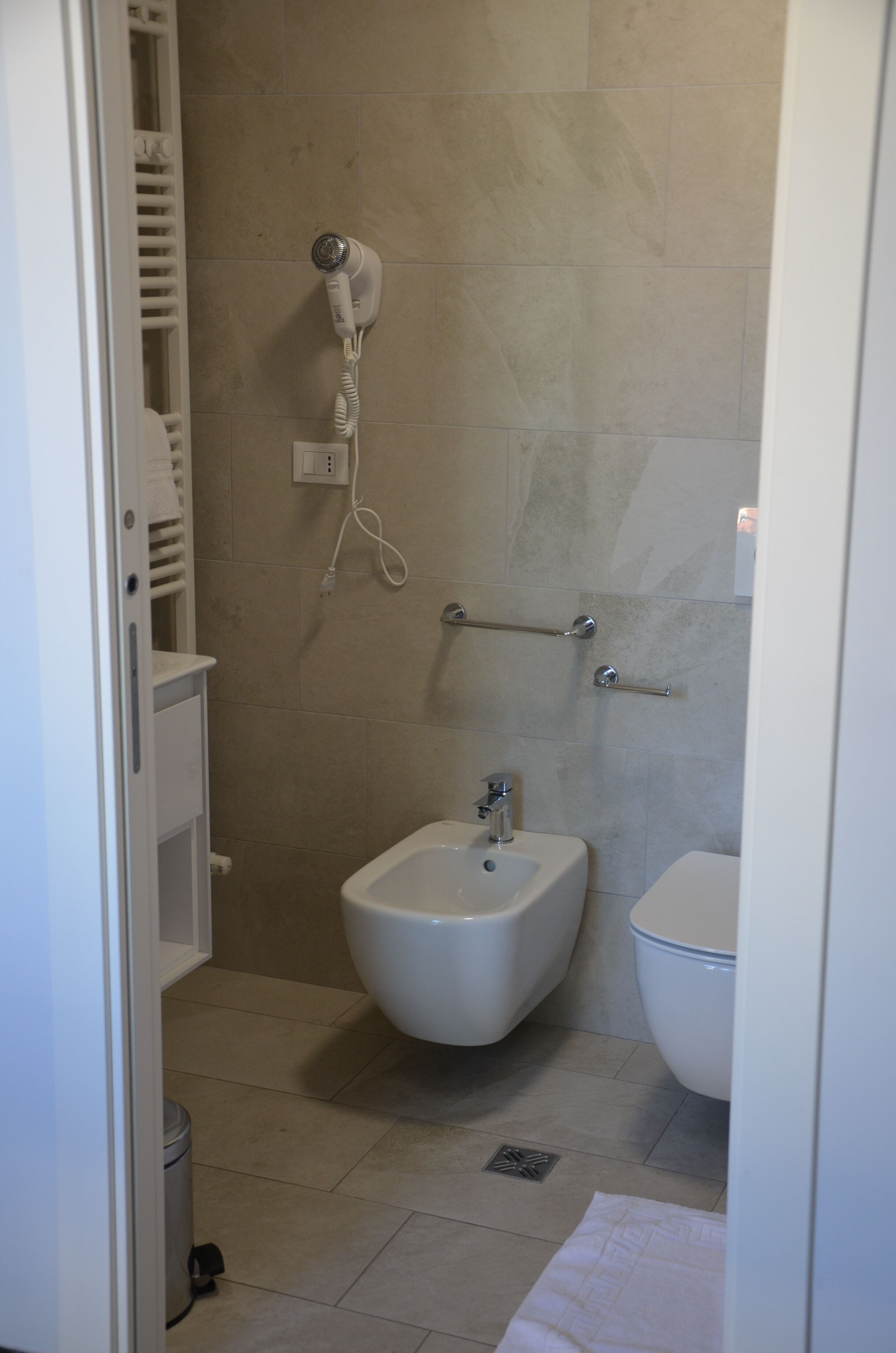 Een badkamer met een bidet, toilet en een aan de muur bevestigde haardroger.