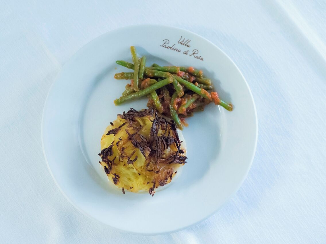 A plate with a dish of fried potatoes and green beans.