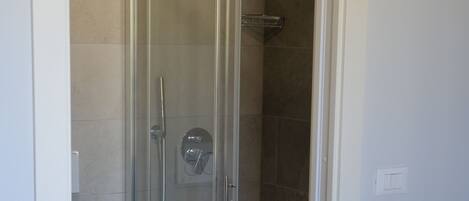A glass-enclosed shower with a white toilet and a white sink in a bathroom.
