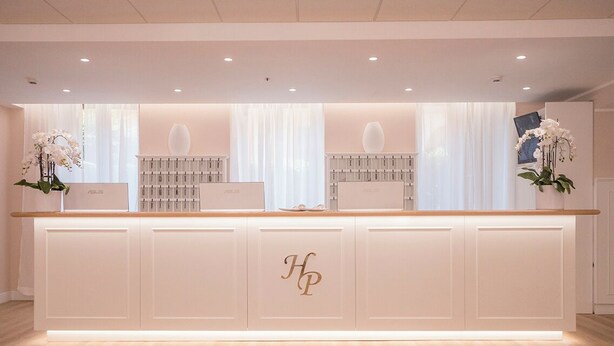 Un comptoir d’accueil au design blanc, orné d’un logo au centre.