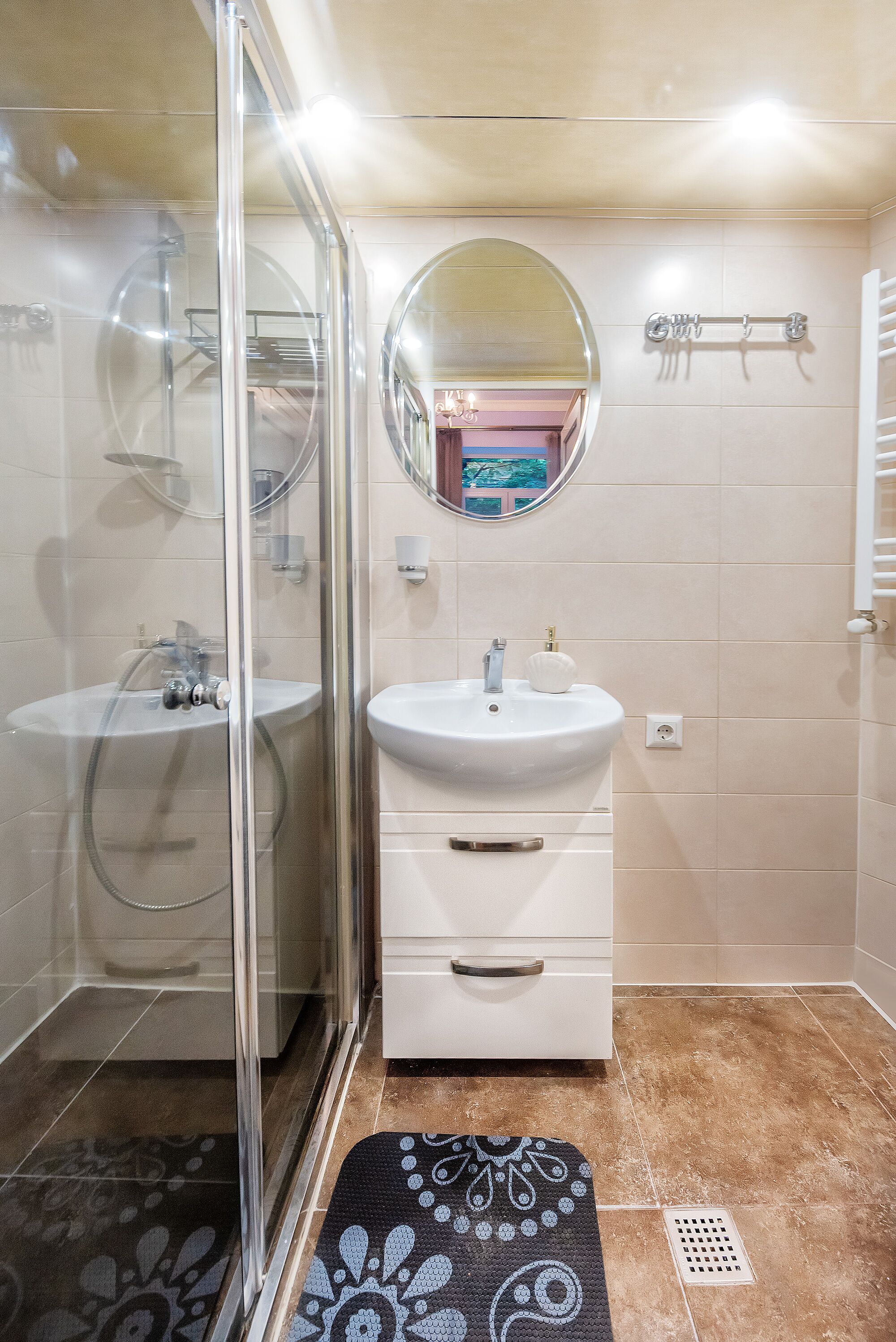 Ein Badezimmer mit Duschkabine, Waschbecken mit Spiegel darüber und Handtuchhalter.