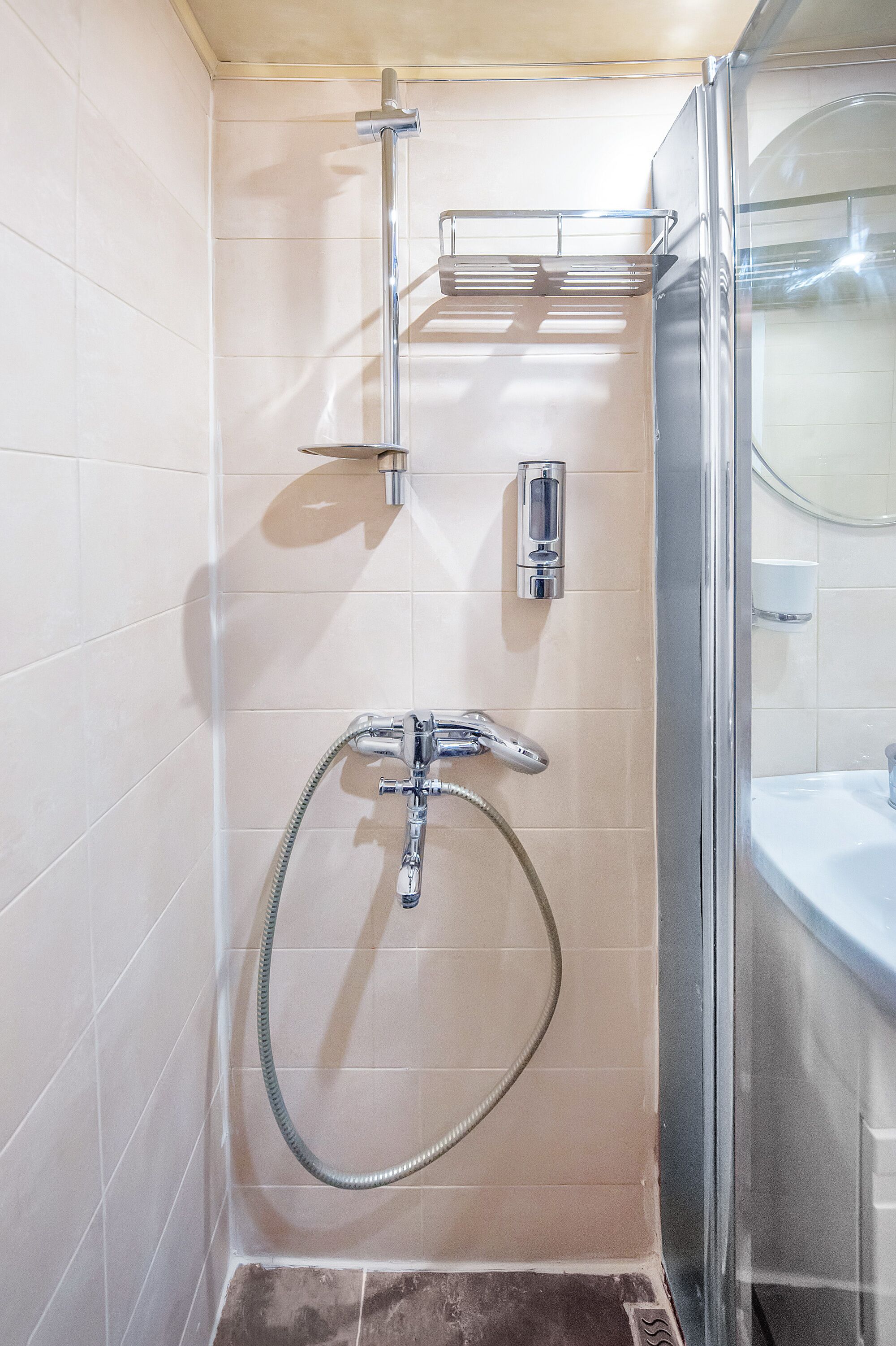 A modern bathroom with a glass shower enclosure, a handheld showerhead, a wall-mounted faucet, and a toilet.