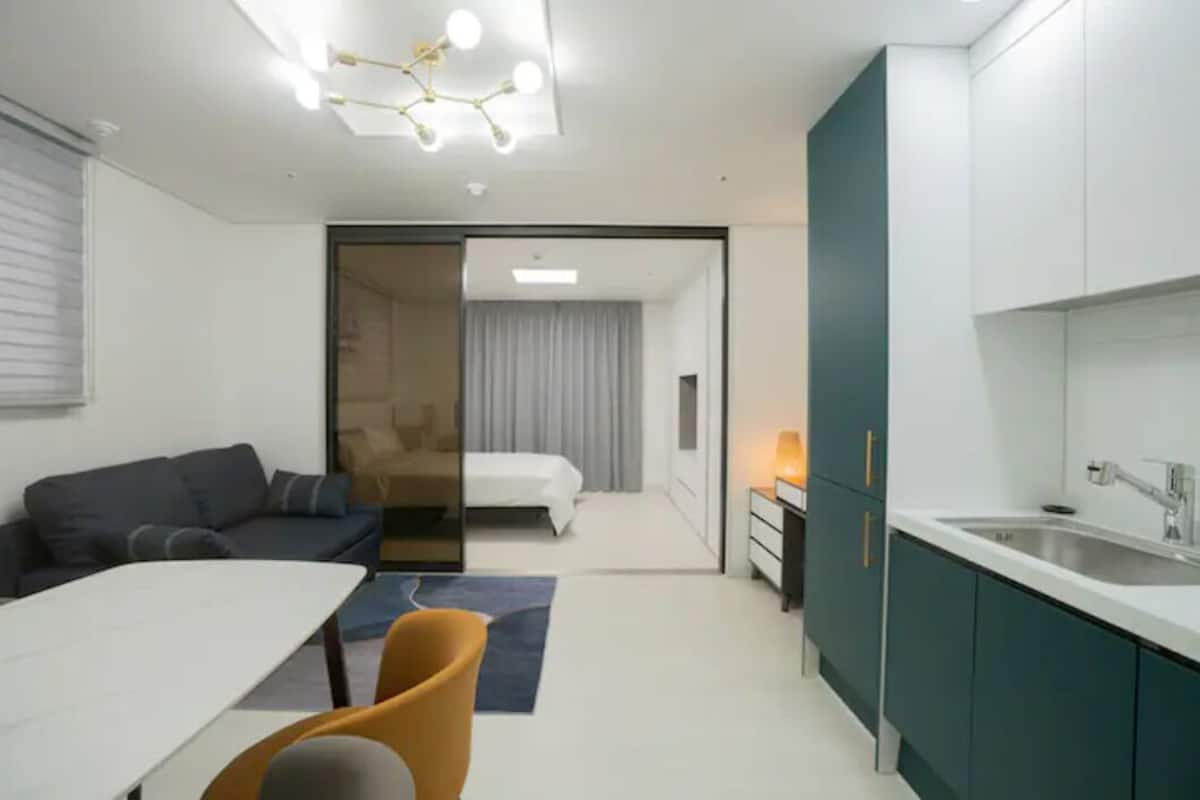 Une chambre d’hôtel de taille réduite comprenant un coin repas, un lit, une kitchenette et une salle de bain.