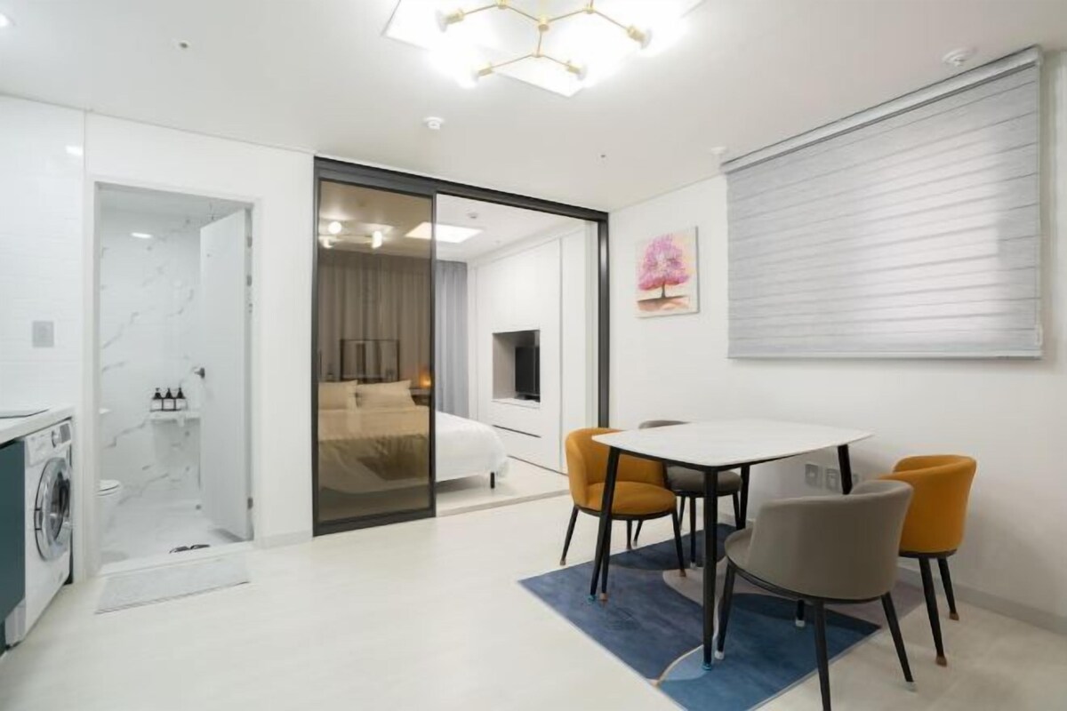 A modern hotel room with a dining area, a bed, and a bathroom.
