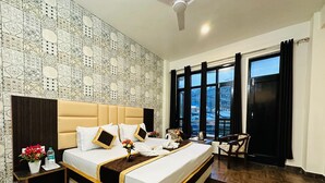 Une chambre d’hôtel avec un grand lit, une tête de lit, une table de chevet, un bureau, une chaise et une fenêtre avec des rideaux.