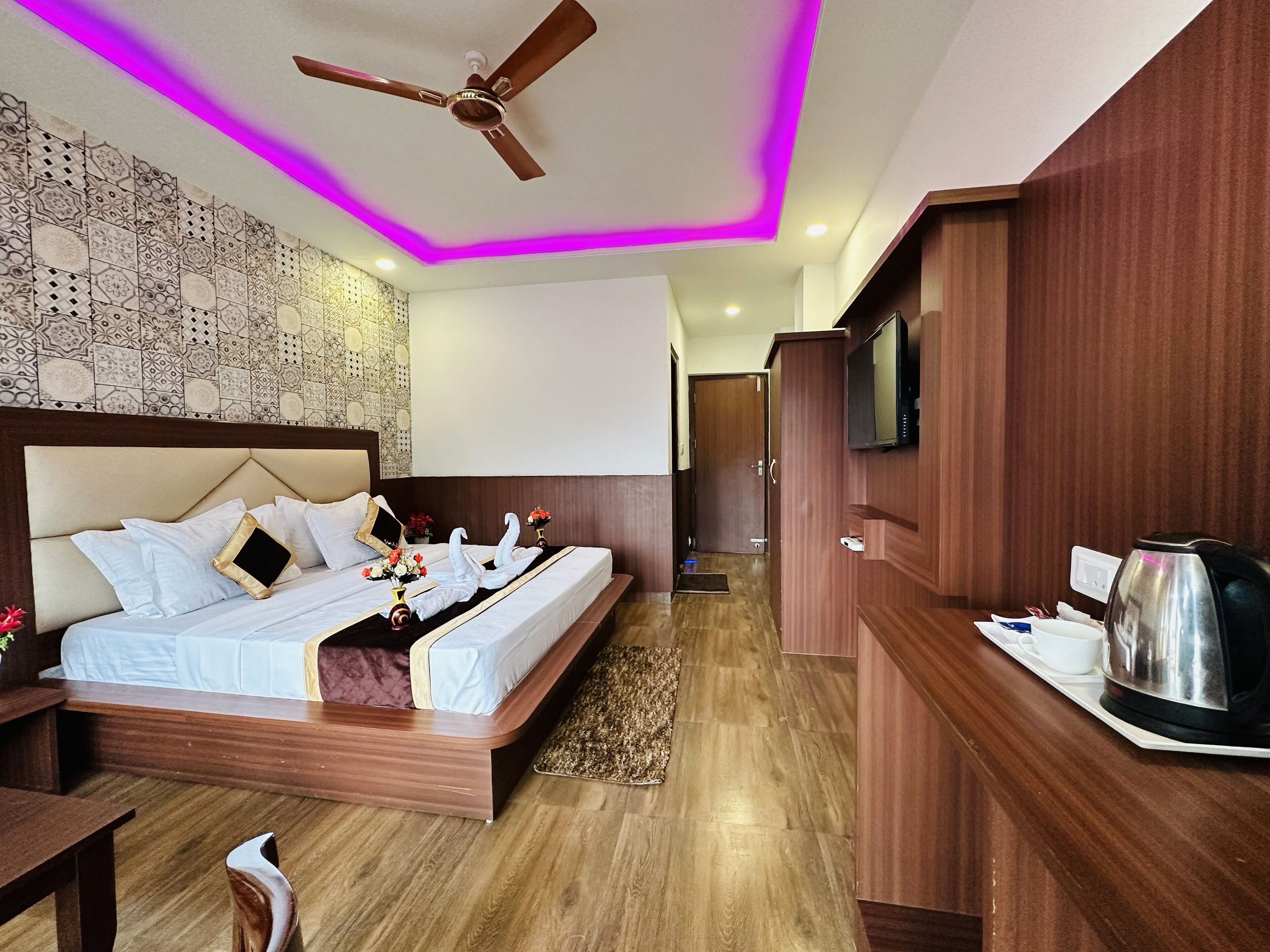 Quarto de hotel com cama, ventoinha no teto, televisão e máquina de café.