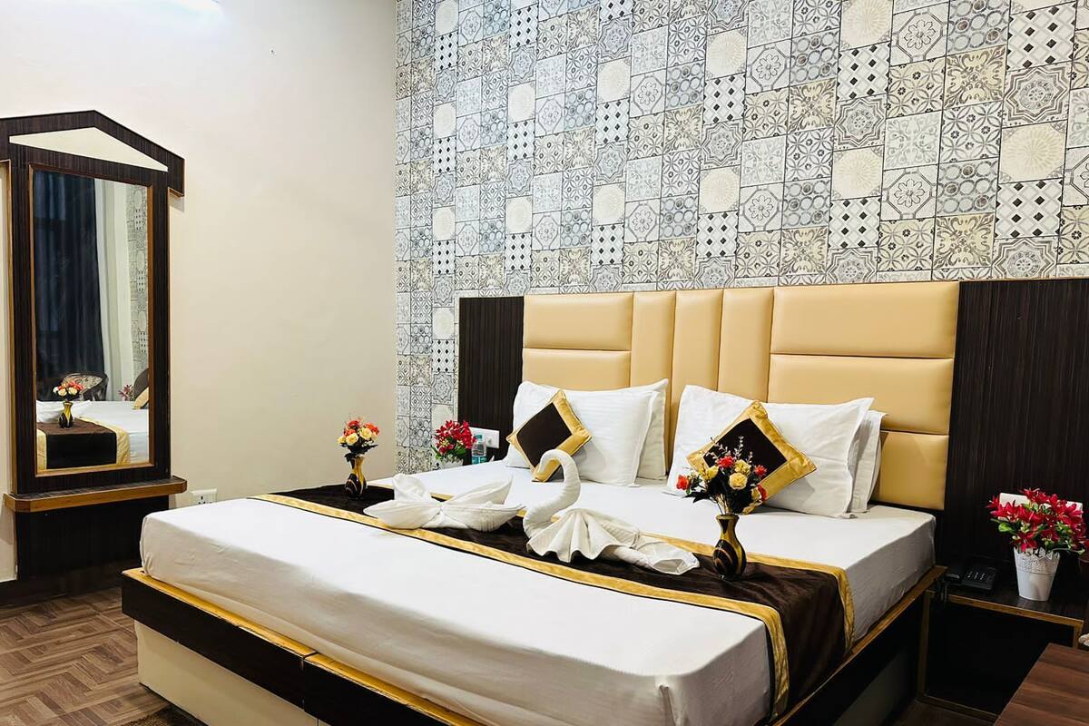 A hotel room with a large bed, a mirror, and a decorative wall.