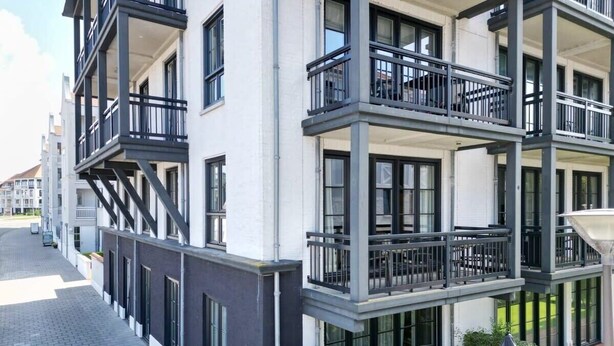 A multi-story building with balconies, a paved walkway, and greenery. - Apartment in Cadzand-Bad | Duinhof V 1-7 (Cadzand)