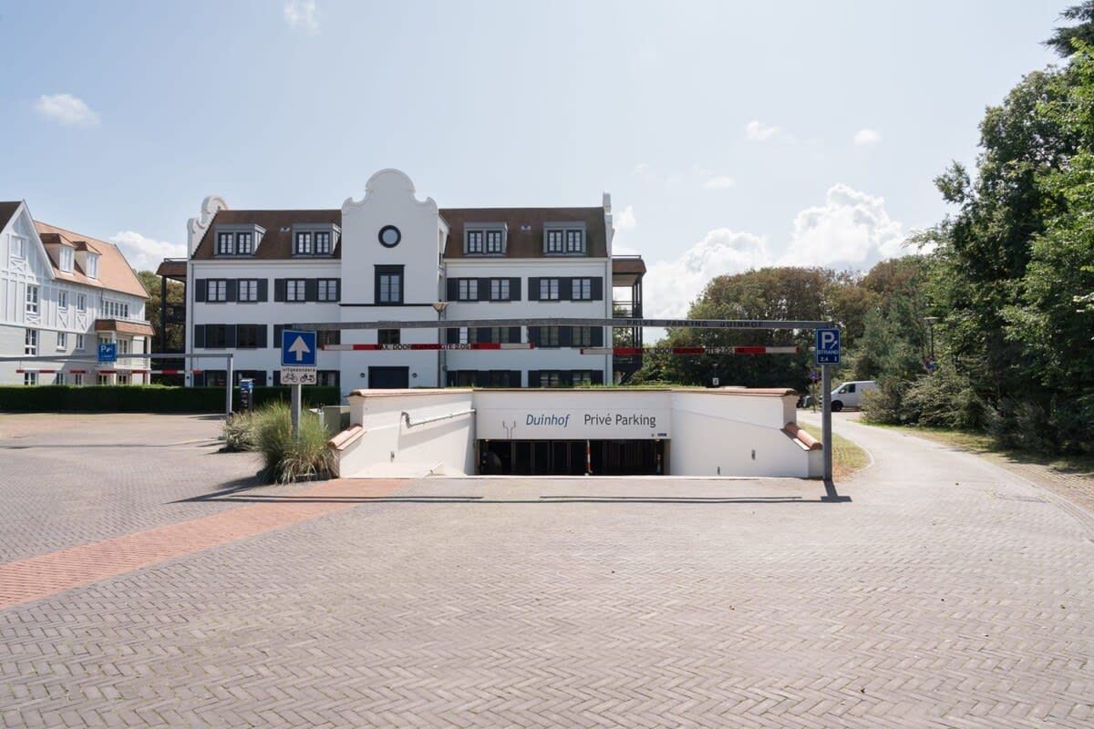 Un bâtiment avec une enseigne indiquant « Duinhoff, parking privé » et un panneau de signalisation de stationnement bleu.