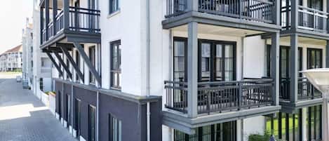 A multi-story building with balconies and a paved walkway.