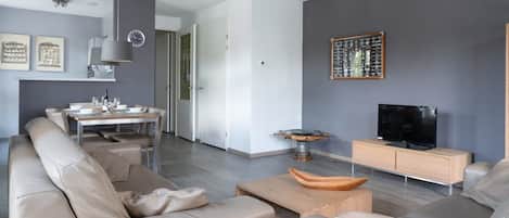 Ein modernes Wohnzimmer mit einer Couch, einem Couchtisch und einem Fernseher.