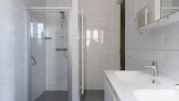 Ein modernes Badezimmer mit einer Duschkabine aus Glas, einem weißen Waschbecken und einem Spiegel.
