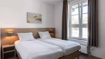 Ein Hotelzimmer mit Doppelbett, Nachttischlampen, einem fenster mit Vorhängen und einem Wandbild.