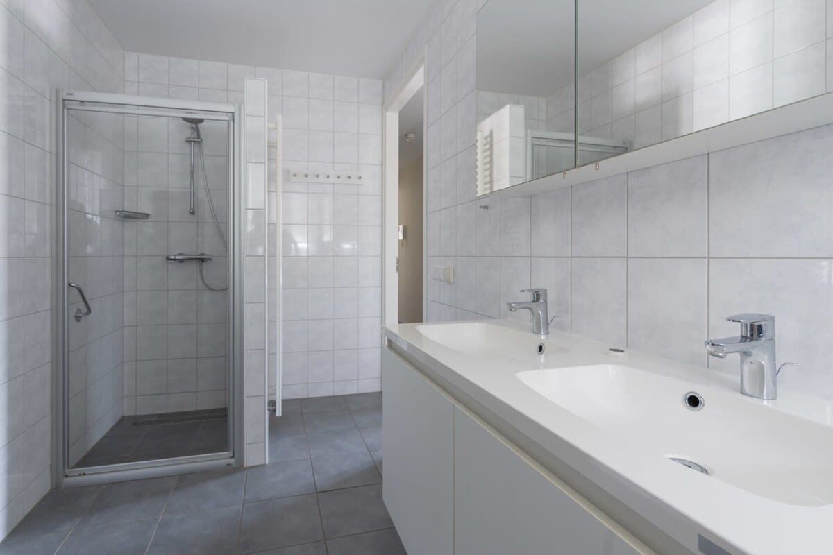 Une salle de bain moderne avec une douche à parois de verre, un double vasque et un grand miroir.