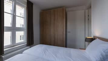 Ein Hotelzimmer mit Bett, Kleiderschrank, Fenster mit Vorhängen und einer Nachttischlampe.