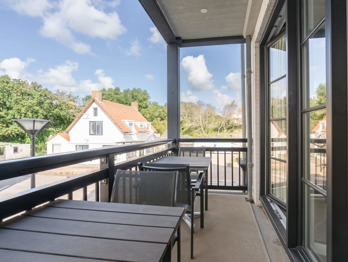 Ein Balkon mit Blick auf Häuser, einem Tisch und Stühlen.