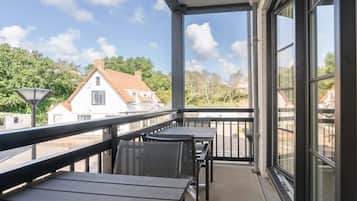 Ein Balkon mit Blick auf Häuser, einem Tisch und Stühlen.