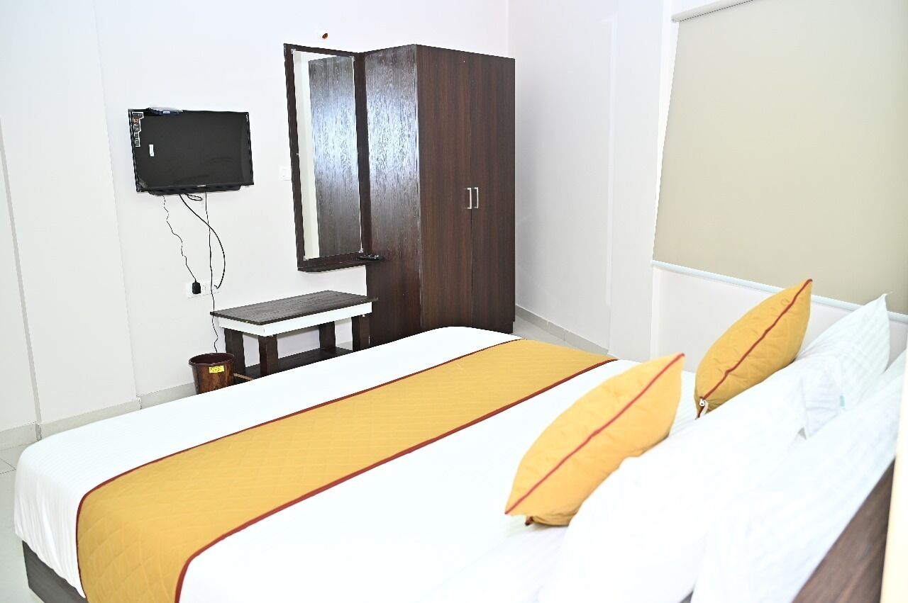 A bedroom with a bed, a desk, a wardrobe, and a TV mounted on the wall.