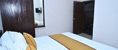 A bedroom with a bed, a wardrobe, and a mirror.