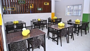 A dining area with multiple tables and chairs, some with yellow balloons. - Hotel SLN Comfort (Tumkur)