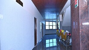 A hallway with a polished floor, wooden ceiling, and large windows allowing natural light. - Hotel SLN Comfort (Tumkur)