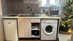 A compact kitchen with a sink, microwave, oven, and washing machine. - CAMPIELLO Apt. by LOC HOSPITALITY (Corfu)