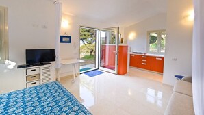 A modern bedroom with a bed, a TV, a desk, and a sliding glass door leading to a balcony. - Bungalow D'elite a Capo Testa (Capo Testa)