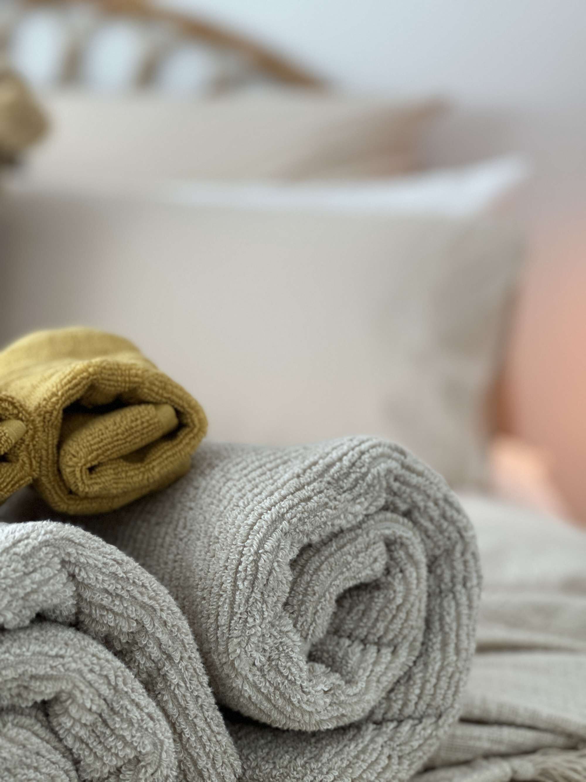 A neatly folded towel and a rolled-up towel on a bed.