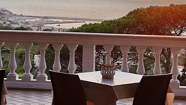 A terrace with a table and chairs, overlooking a coastal view during sunset. - Villa Antonietta Ischia  (Forio)