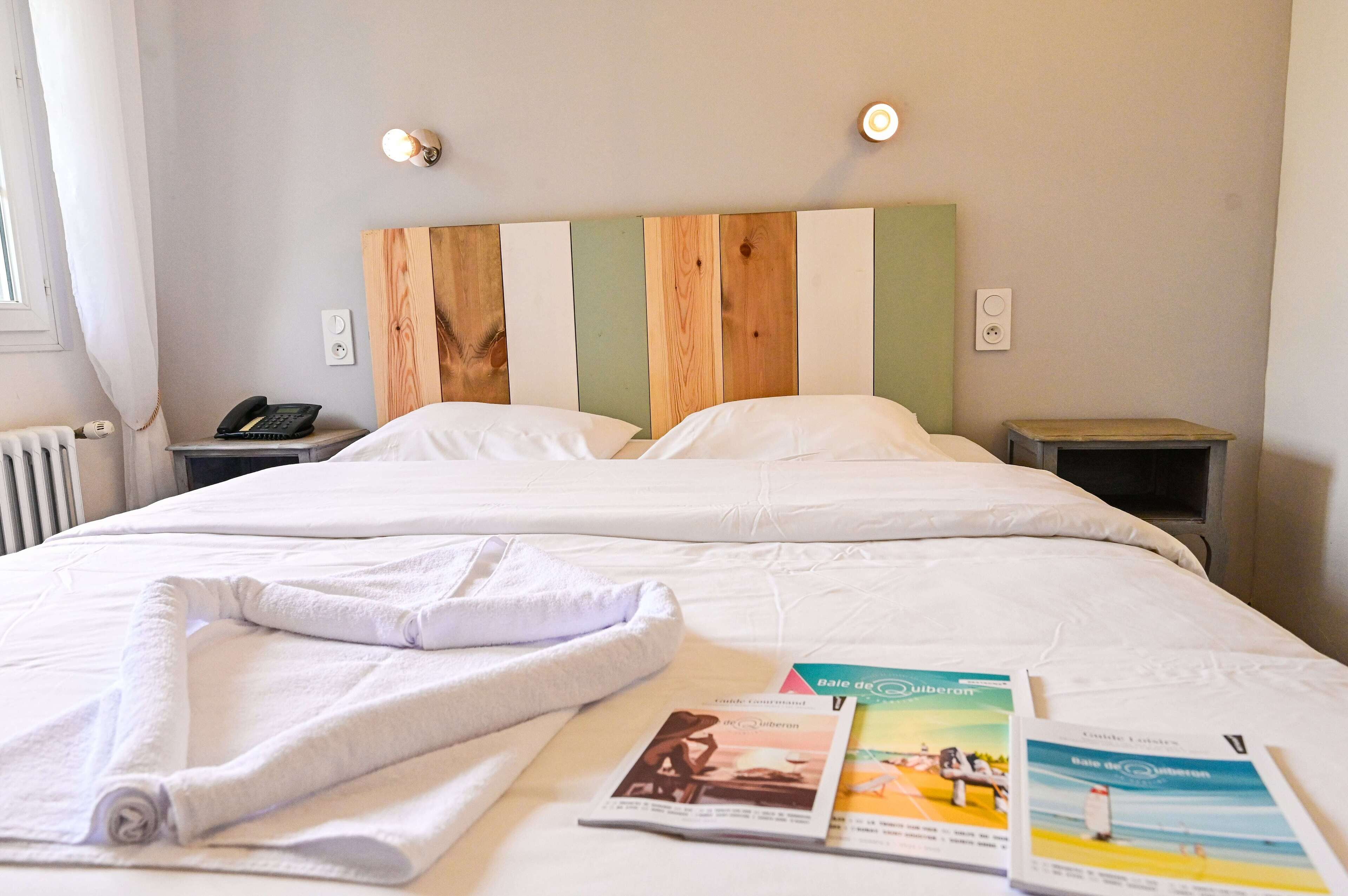 A hotel room with a large bed, two bedside tables, a telephone, and a radiator.