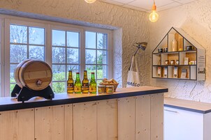 A bar area with wooden counter, bottles, and a barrel.