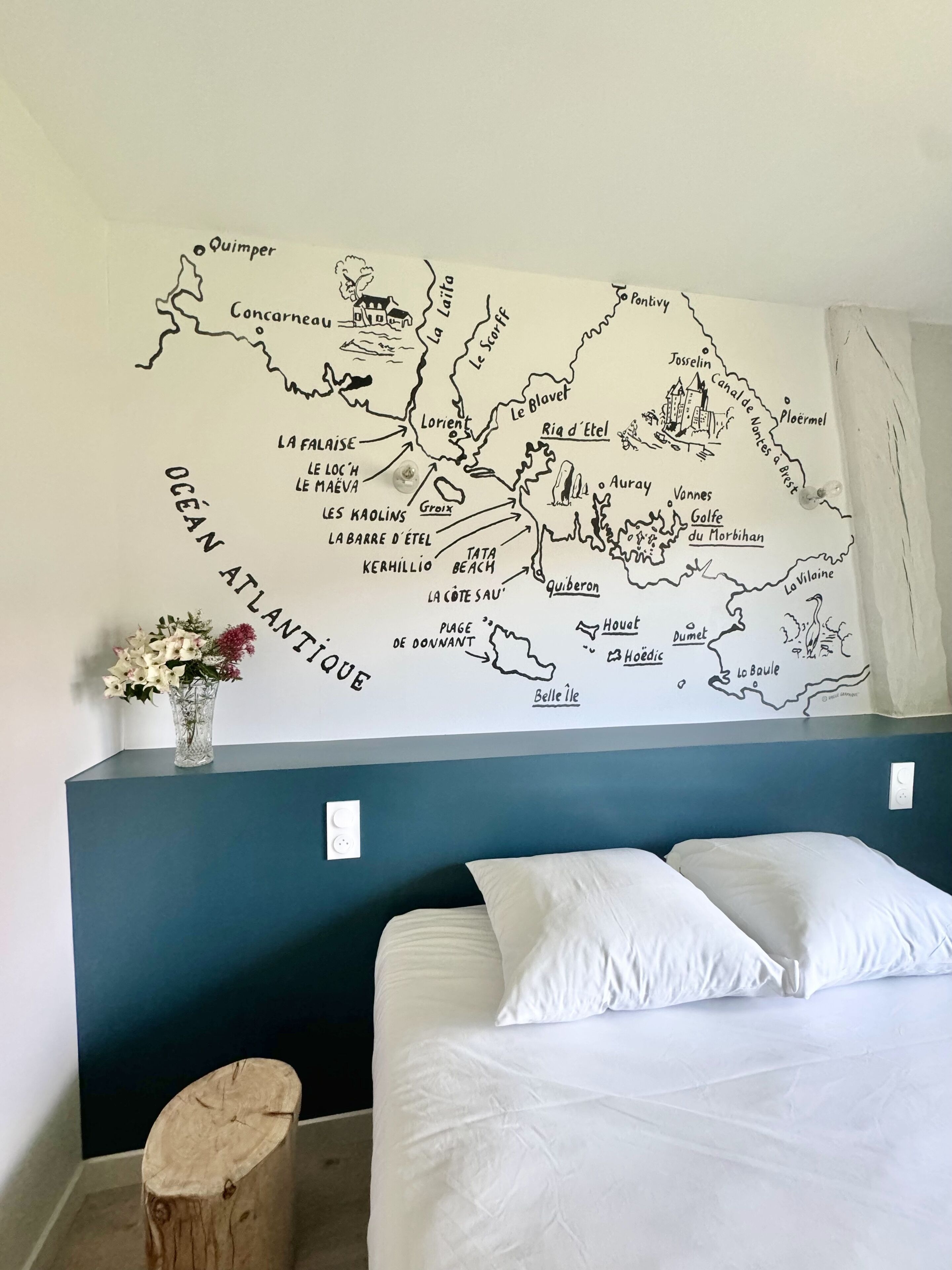 A bedroom with a bed, a nightstand, and a wall map of the Atlantic Ocean.