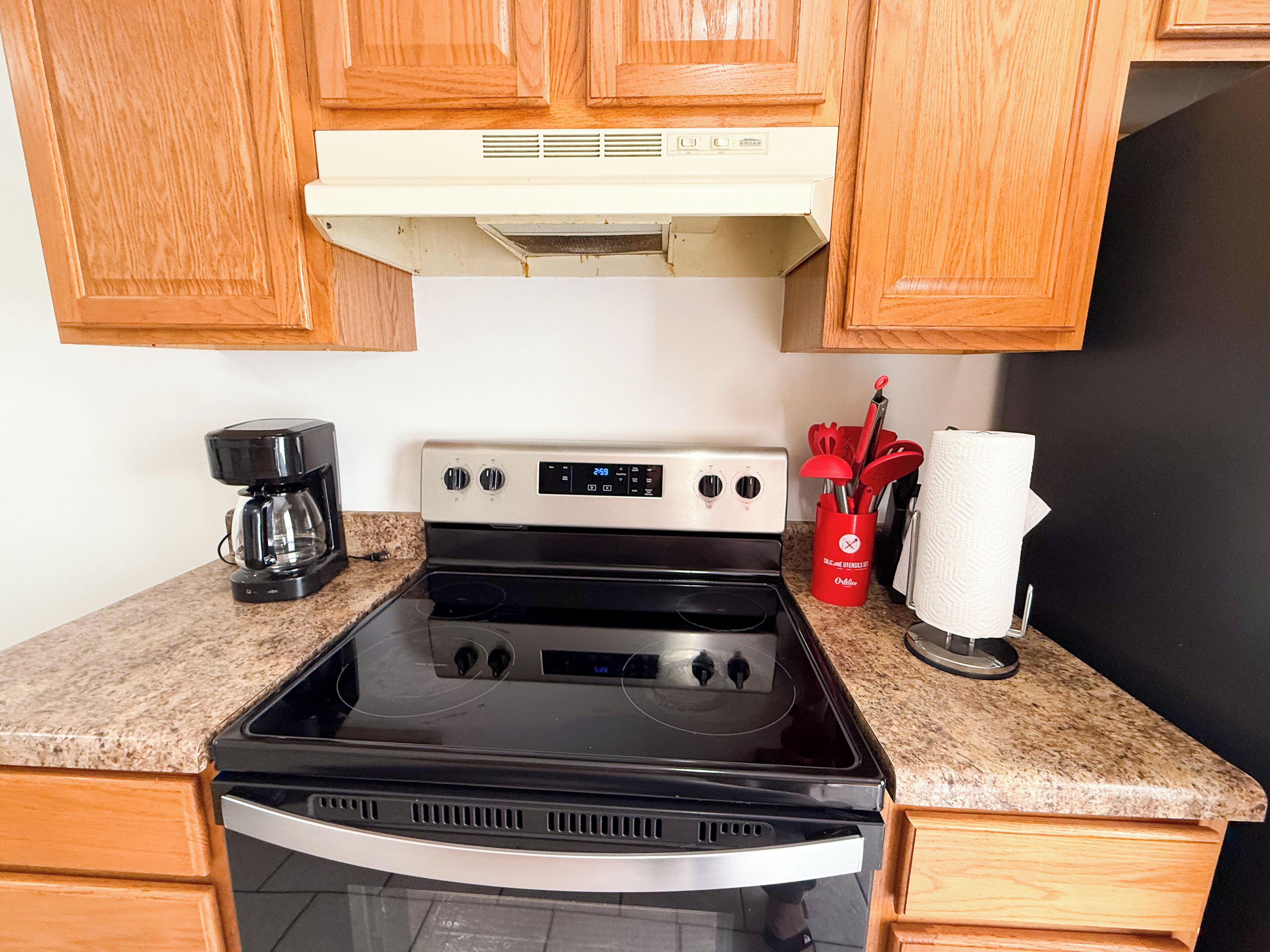 A kitchen with a stove, microwave, and a red utensil holder.