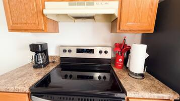 A kitchen with a stove, microwave, and a red utensil holder.