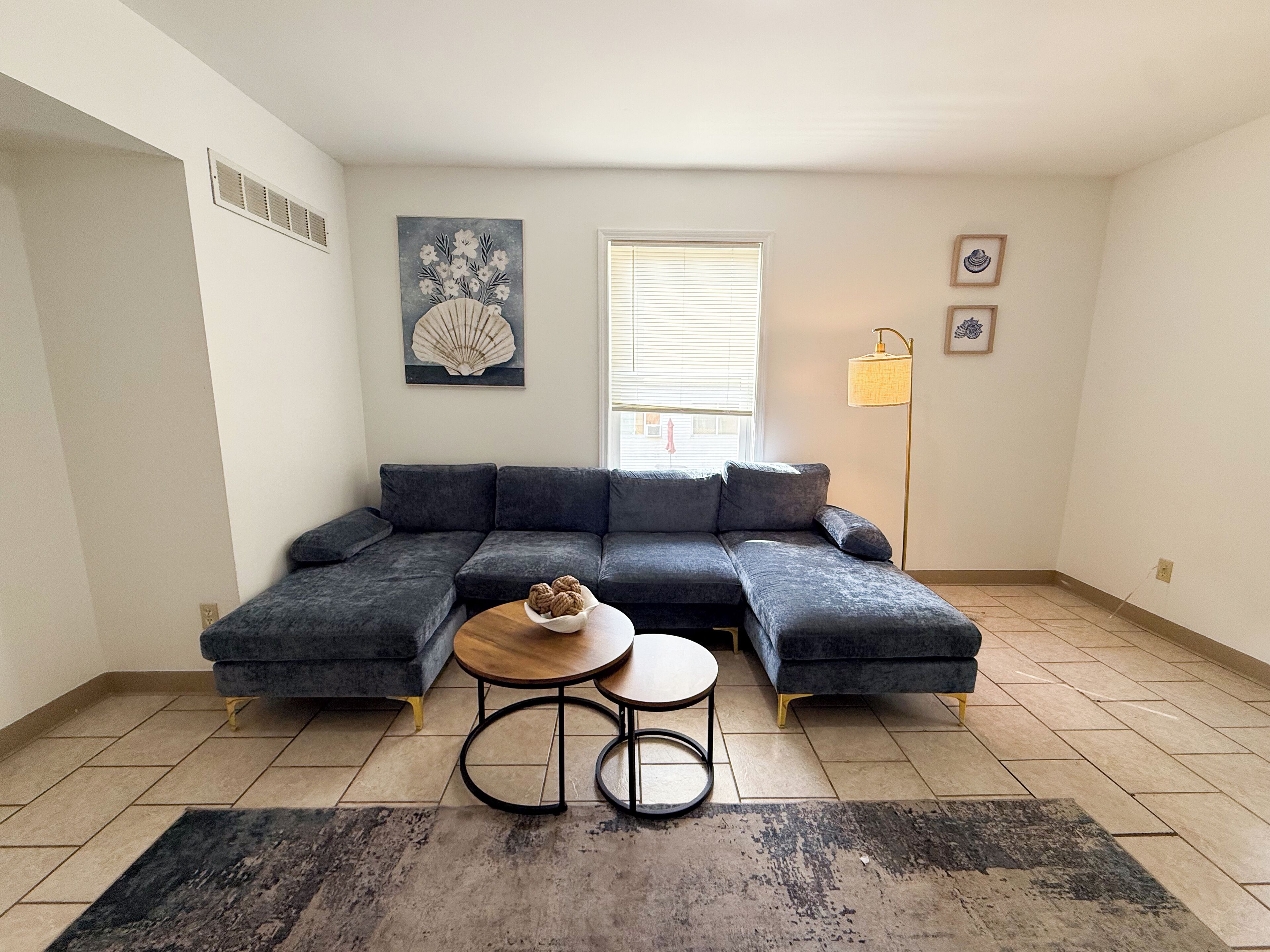 Una sala de estar moderna con un sofá modular, una mesita de centro redonda y una lámpara de pie.